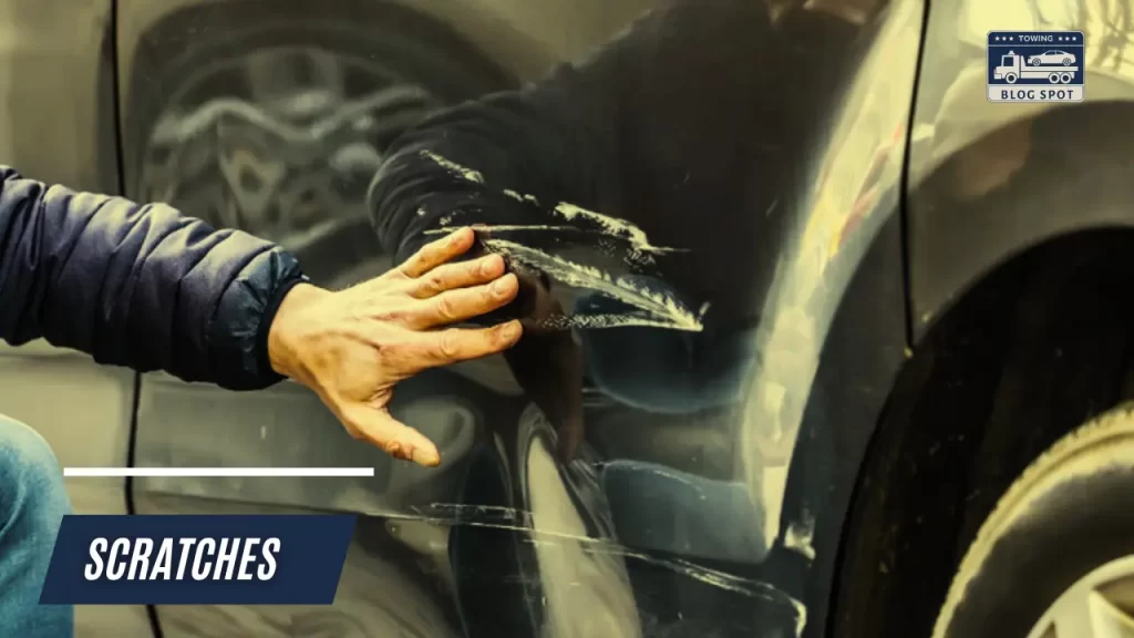 a man seeing his car scratches and considerring to contact the towing company that has caused this issue . 