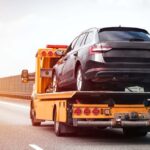 Tow truck operator lifting a broken-down car
