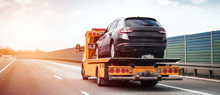 Tow truck operator lifting a broken-down car