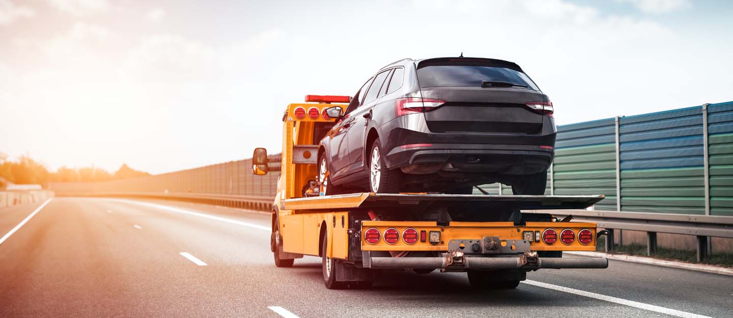 Tow truck operator lifting a broken-down car