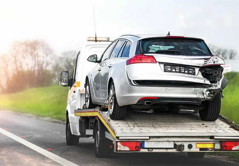 Car being towed after accident showing insurance covered roadside assistance recovery